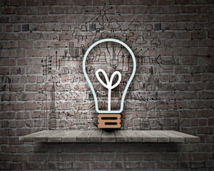 Conceptual image of light bulb on wall with sketches of ideas